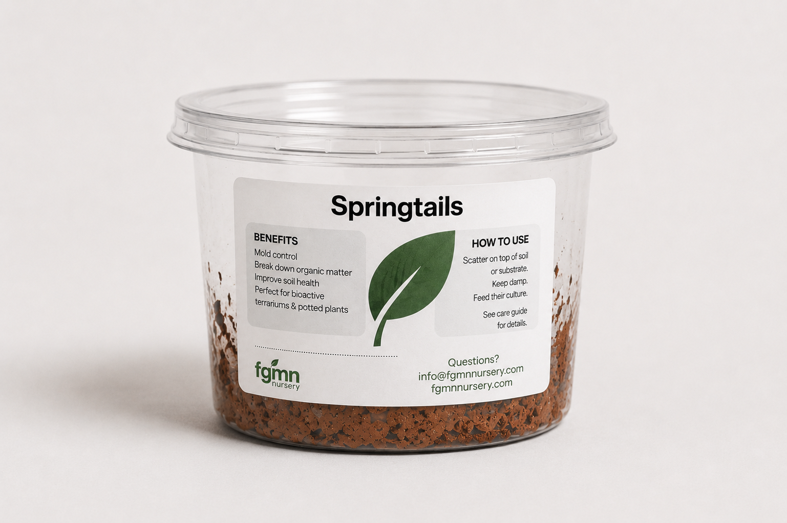 A clear plastic tub filled with dark, irregularly shaped organic moss control granules labeled 'Springtails' by fgmn nursery, on a light gray background.